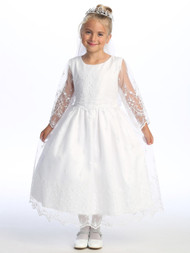 Little girl smiling in a white Communion dress with embroidered tulle.