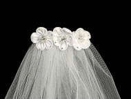 White satin flowers at the top of a white veil.