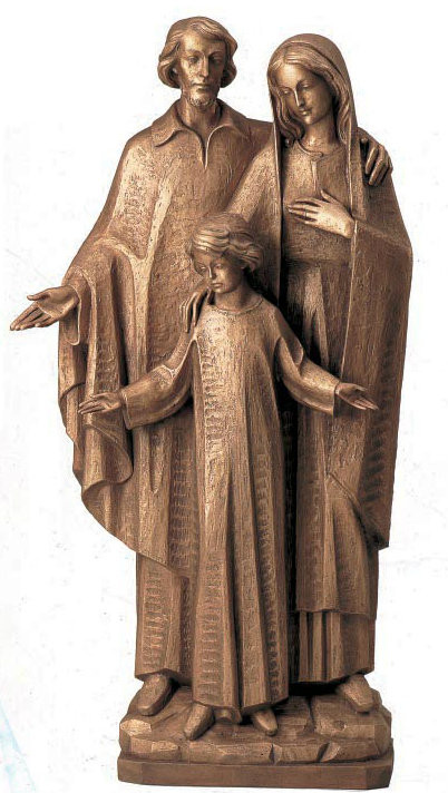 Bronze sculpture of Saint Joseph and Virgin Mary looking down on Child Jesus. Mary standing beside them. 
