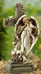 A memorial angel leaning against a cross that is covered in roses with a white dove resting on it.