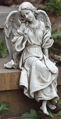 Statue of angel sitting on a ledge looking left.