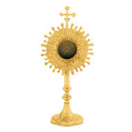 Image of a gold plated reliquary with a decorative base and staff. Center is a starburst design with a cross on top.
