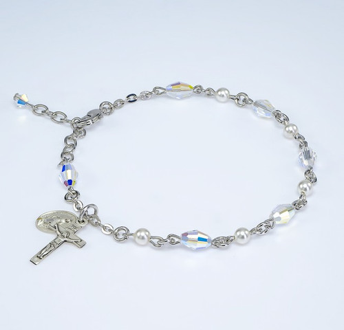 Deluxe Rosary Bracelet made with 6mm White Pearl and 6x9mm Aurora Borealis Oval Swarovski Crystal Beads. Choose from all sterling silver links, chains and exclusive designed Sterling Silver Miraculous Medal and Crucifix or Rhodium plated brass wire and chain with exclusive designed Sterling silver Miraculous Medal and crucifix. Presented in a deluxe velour metal gift box. Made in the USA