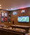 The ultimate upscale basement game room, sports den, or "man cave" that radiates a warm, traditional, and welcoming atmosphere. The space emphasizes comfort, entertainment, and personal hobbies, utilizing full-wall Spirit Birch wood paneling to create a classic, cozy clubroom feel.