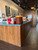 The MCM Spirit Birch paneling has a smooth, lightly finished surface with a subtle sheen that enhances the wood’s natural character. Narrow vertical seams define the individual boards, creating a clean, orderly appearance. A slim, dark wood trim runs along the bottom of the counter, providing a neat transition to the flooring.