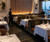An elegant, high-end fine dining restaurant that masterfully blends mid-century modern sophistication with contemporary luxury. The space utilizes a rich combination of natural textures—Spirit Birch wood paneling, plush velvet, smooth leather, and dark stone—to create an intimate, upscale atmosphere with a sweeping urban backdrop.
