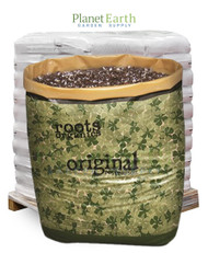A large Roots Organics soil bag filled with potting mix, in front of a pallet of white bags.