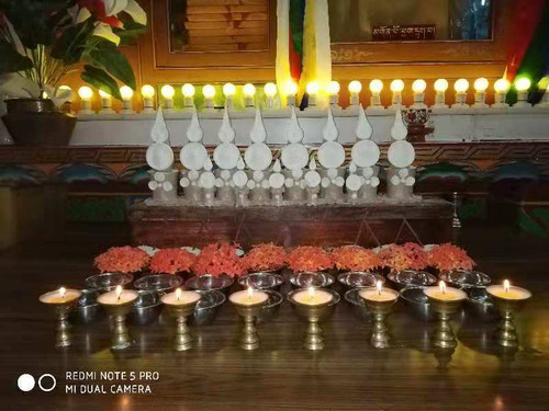 Tibetan Buddhist shrine with offerings, candles, flowers and other blessed objects.